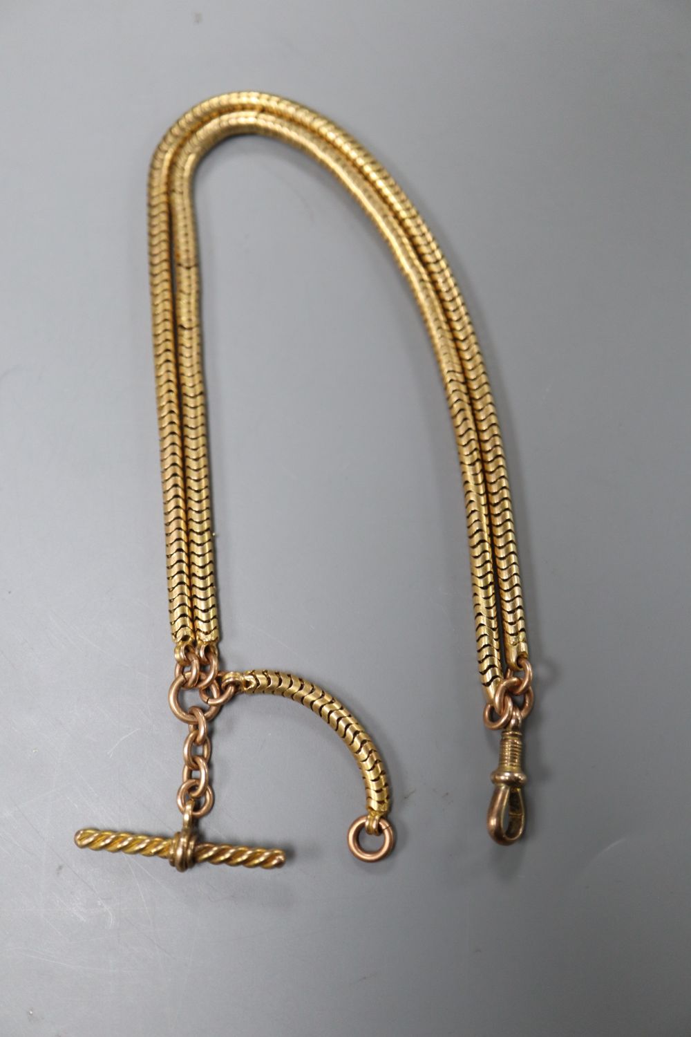 An early 20th century yellow metal snakelink chain, with added T-bar, 47cm, gross 21.4 grams.